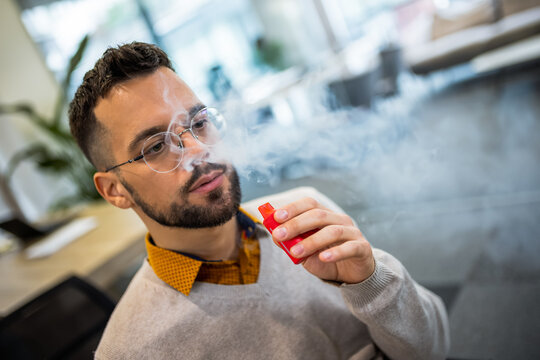 Young man smoking an electronic cigarette to quit tobacco. Vape man. Alternative nicotine-free smoking concept
