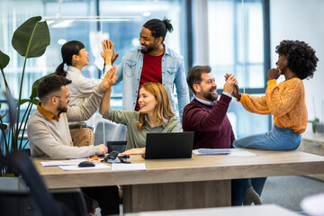 International workers group high five after finishing important project.