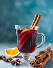 Mulled red wine with spices on blue background. Selective focus. Copy space