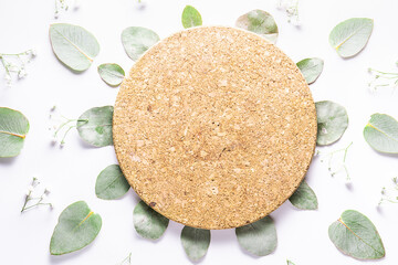 Eco friendly zero waste wooden cosmetic podium, decorated with fresh green eucalyptus leaves and flowers top view, copy space for your design.
