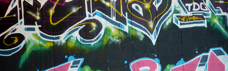 Colorful background of graffiti painting artwork with bright aerosol outlines on wall. Old school street art piece made with aerosol spray paint cans. Contemporary youth culture backdrop