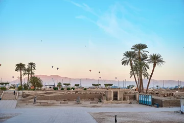 Foto op Plexiglas sun rise from luxor temple with palm tree and cloudy blue sky and hot air ballon in the background, Luxor, Egypt. © Mostafa Eissa