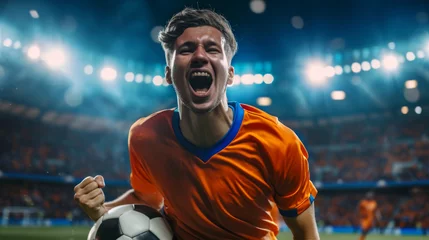 Fotobehang excited soccer player in an orange jersey is holding a soccer ball, celebrating with a stadium in the background © MP Studio