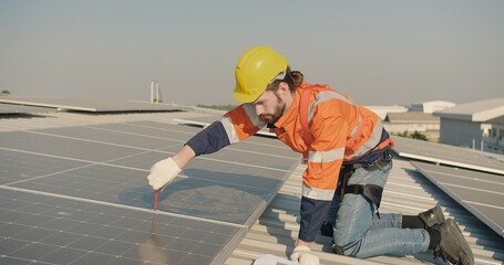 engineer Technician in safety gear installs solar panels on a roof under a clear sky, with a...