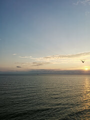 Tranquil Evening Seascape, Summer Sunset Casting Warm Glow Over Calm Waters with Clouds, Serene Beauty of Dusk