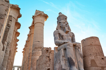 Seated statue of Ramesses II by the First pylon of the Luxor Temple, Egypt. Columns and statues of the Luxor temple main entrance, first pylon, Egypt