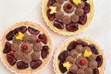 Fototapeta premium Shortbread tartlets decorated with whipped ganache and fruits (cherries, strawberries and nectarines cut out into a butterfly shape). Summer romantic baking