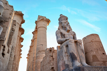 Seated statue of Ramesses II by the First pylon of the Luxor Temple, Egypt. Columns and statues of the Luxor temple main entrance, first pylon, Egypt
