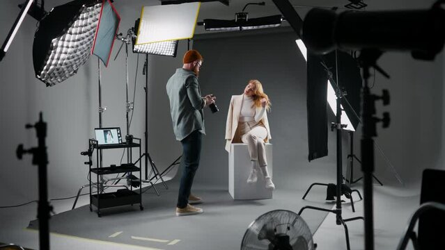 Photographer showing photos to fashion model while working in studio for clothes brand and designer social media blog