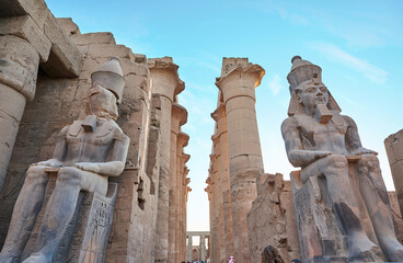 Seated statue of Ramesses II by the First pylon of the Luxor Temple, Egypt. Columns and statues of...