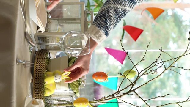 Young woman is setting easter festive table with bunny and eggs decoration