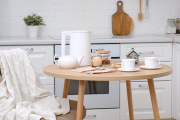 Home spring easter interior in kitchen. Beige chair with white cover, white electric kettle, hot...