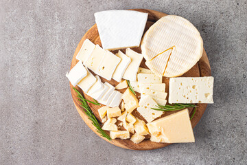 Wooden board with various cheese and olives. Brie. Camembert. Parmesan, feta, blue cheese. Italian, French cheese.