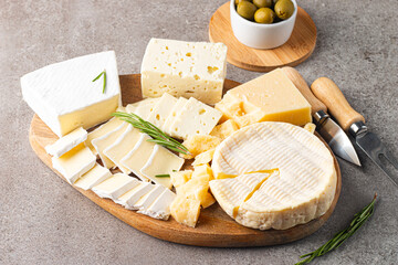 Wooden board with various cheese and olives. Brie. Camembert. Parmesan, feta, blue cheese. Italian, French cheese.