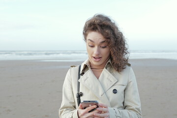 portrait of a surprised, anxious young woman  looking at a  phone seeing bad news or photo