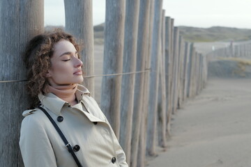Obraz premium Close up portrait of a beautiful young woman taking deep breaths with eyes closed on a sandy winter beach