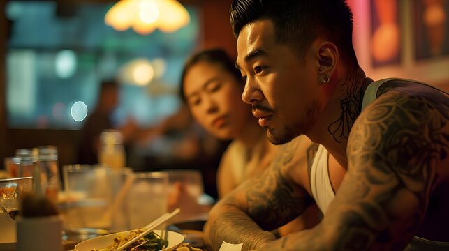 portrait of a muscular korean man with tattoos eating with his cute girlfriend in resturant