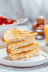 Toast sandwich with gouda cheese and turkey ham  on a bright background with ingredients in blurry background. Served with orange juice  and eggs