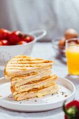 Toast sandwich with gouda cheese and turkey ham  on a bright background with ingredients in blurry background. Served with orange juice  and eggs