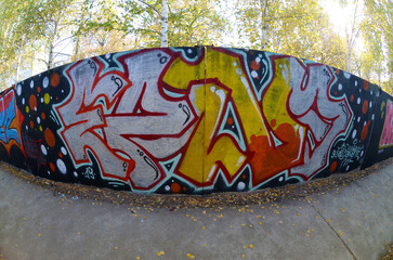 Fisheye shot of street art graffiti drawing on wall. Spray art artwork with different colors and outlines. Illegal vandalism concept