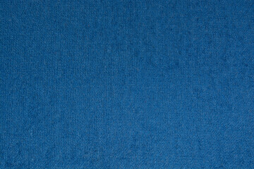 The texture is terry fabric in blue. The background is solid blue. Background texture of knitted...