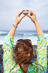 woman meditating on beach shore and holding crystal heart