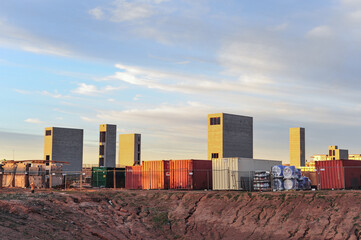 Overview of the construction site of a multifamily development, featuring brick towers, various construction materials, and shipping containers