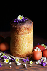 Homemade easter cakes with spring flowers and red eggs on dark moody rustic background, traditional...