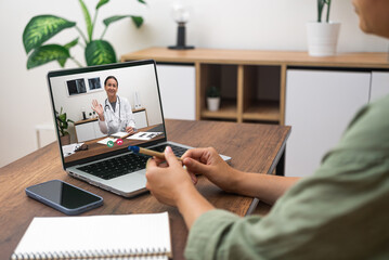 Patient engaging in a telemedicine session with a doctor on a laptop at home.