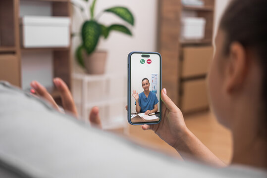 Virtual medical consultation with a friendly doctor greeting patient via smartphone.