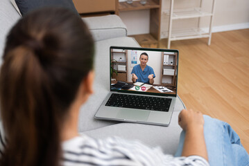 Over-the-shoulder shot of a telemedicine consultation with a doctor explaining on a laptop, exemplifying modern medical care.