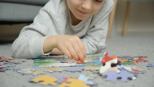 A child putting together puzzles while lying on the carpet. Educational classes for preschoolers and primary school children