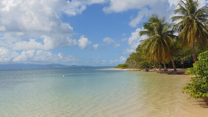 La plage de sable blanc et la mer turquoise sous le ciel nuageux