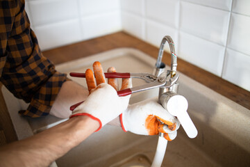 Uniformed plumber is using a wrench to repair a water pipe under the sink. Maintenance concept:...