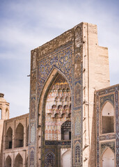 Fototapeta na wymiar Element of the facade of a madrasah made of brick with mosaic cladding in the ancient city of Bukhara in Uzbekistan, architecture in oriental style, facade of a mosque with patterns and ornaments