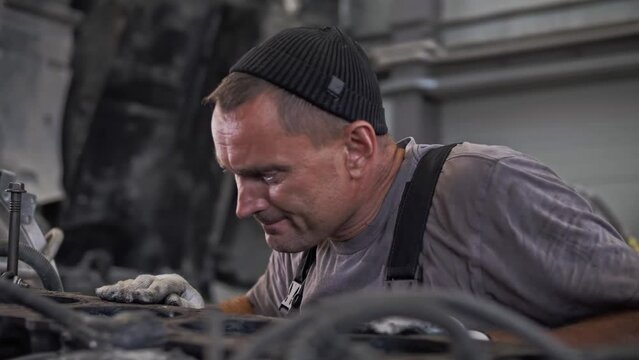 Engine mechanic inspects a huge truck engine