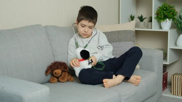 Little kid doctor listening to toy plush dog with stethoscope