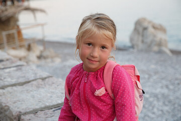 Cute little girl in pink against the background of the sea.