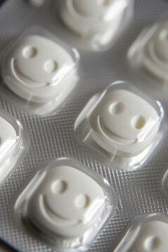 Pill tablet packaging featuring cheerful white smiley face pills shaped like peapods