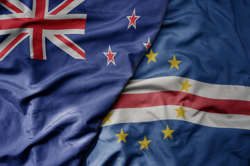 big waving national colorful flag of cape verde and national flag of new zealand .