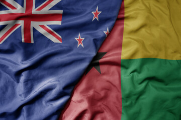 big waving national colorful flag of guinea bissau and national flag of new zealand .
