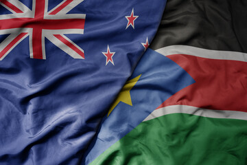 Fototapeta premium big waving national colorful flag of south sudan and national flag of new zealand .