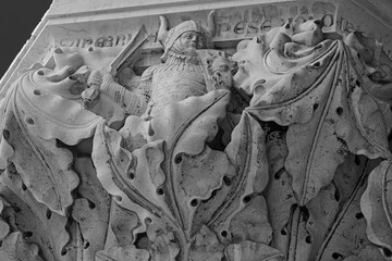 Venice, Italy, Sept. 17, 2023: A 14th century Doges Palace portico column depicts the deadly sin of pride as a warrior wearing a horned helmet and holding a dragon shield. - obrazy, fototapety, plakaty