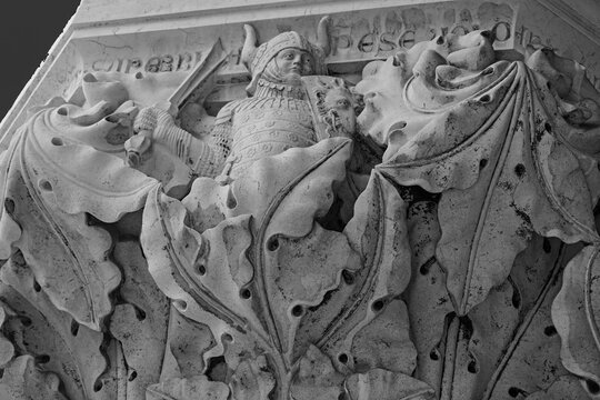 Venice, Italy, Sept. 17, 2023: A 14th century Doges Palace portico column depicts the deadly sin of pride as a warrior wearing a horned helmet and holding a dragon shield.
