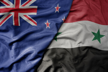 big waving national colorful flag of syria and national flag of new zealand .