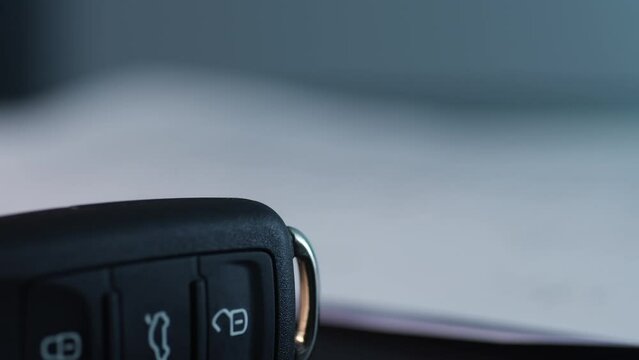 Hand signs a document beside a car key, car-related financial agreement. Close-up, shallow dof.