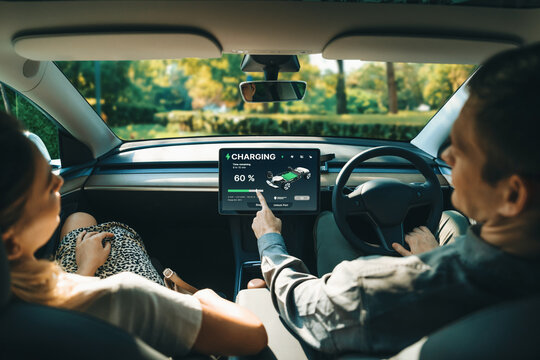 Electric car driver checks battery charging status, range and charging limit on app screen in the car. Smart technology device show EV car recharging data of electric storage in car battery innards.