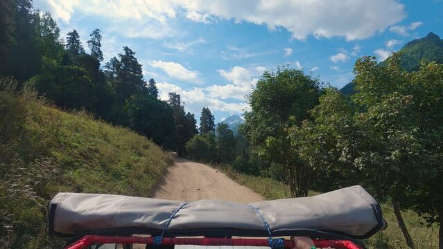 SUV driving on a narrow mountain road. First-person view of a man standing in the car with an open roof. Man admiring mountain peaks. Summer off road travelling