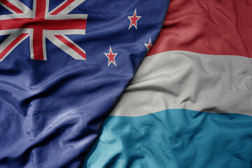 big waving national colorful flag of luxembourg and national flag of new zealand .