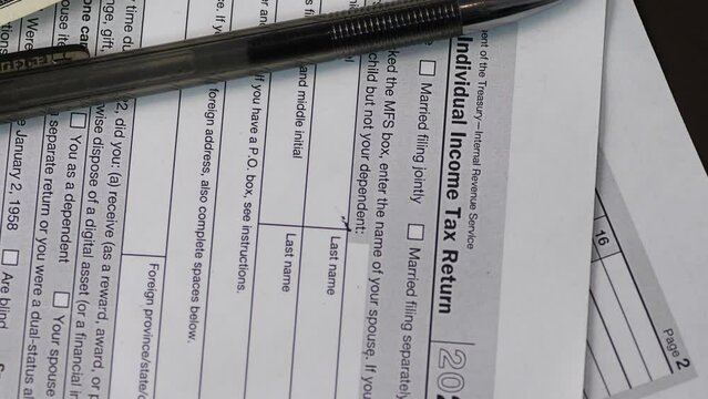 tax form 1040 pen and dollar bills rotating close up .filling out tax form .paying taxes by american citizens